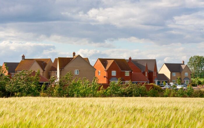 field of barley with new homes in the background