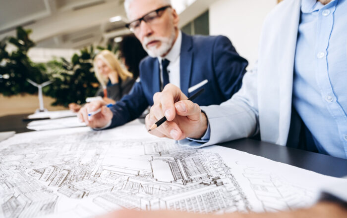 Architects and engineers reviewing blueprint in modern office, selective focus ,close up